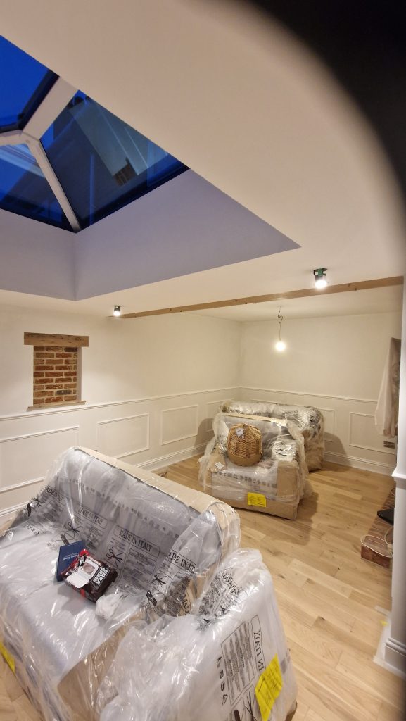 A garden room painted in off white with panelled wainscoting and a roof lantern overhead